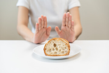 Gluten allergy, asian young woman hand push out, refusing to eat white bread slice on plate in...