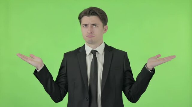 Businessman showing helplessness on green background.Young businessman shrugging shoulders on green screen background