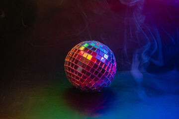 A vibrant, illuminated disco ball casting reflections in a smokymisty party or nightclub setting