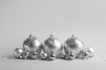 Silver Christmas baubles with beads garland on grey background