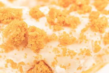 Close-up image of a frosted donut with orange sprinkles, vibrant colors, and textured surface