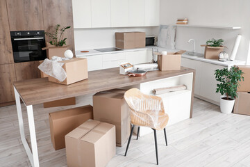 Interior of kitchen with counters, table and cardboard boxes on moving day