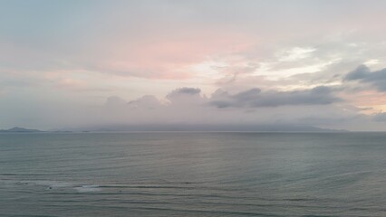 Beautiful cloudy red sunrise over sea with beach, waves and mountains in the background. Impressive structure texture in the sky