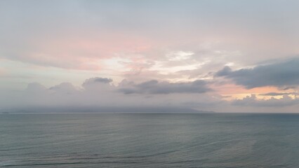Beautiful cloudy red sunrise over sea with beach, waves and mountains in the background. Impressive structure texture in the sky