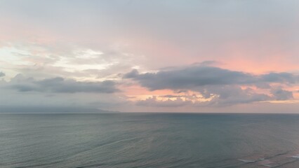Beautiful cloudy red sunrise over sea with beach, waves and mountains in the background. Impressive structure texture in the sky