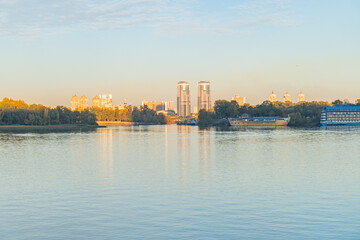 Fototapeta premium A captivating shot showcasing urban beauty, with a reflective body of water, modern high-rise buildings, distinctive tower, and a tranquil sky at either sunrise or sunset