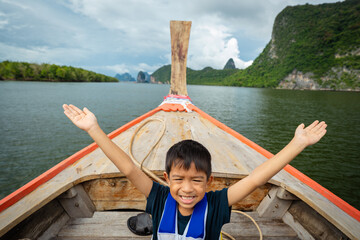Little asian kid boy travel in sea bay with long tail wooden boat island sea