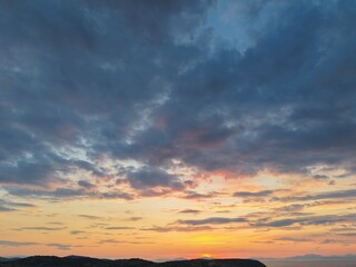 Beautiful cloudy red sunrise over sea with beach, waves and mountains in the background. Impressive structure texture in the sky