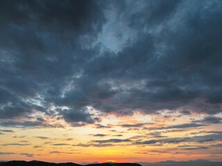 Beautiful cloudy red sunrise over sea with beach, waves and mountains in the background. Impressive structure texture in the sky