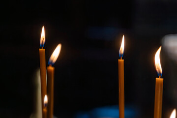 Close-up image of three lit candles in a solemn setting, casting warm shadows Realistic style with...