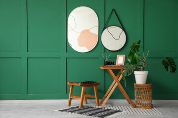 Mirrors on green wall, stool and table in interior of room