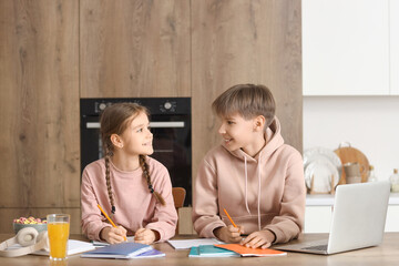 Teenage boy with his sister doing homework in kitchen