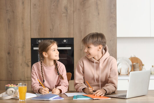 Teenage boy with his sister doing homework in kitchen