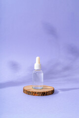 Facial serum on wooden stand on purple background with shadows. Natural cosmetics, skincare concept