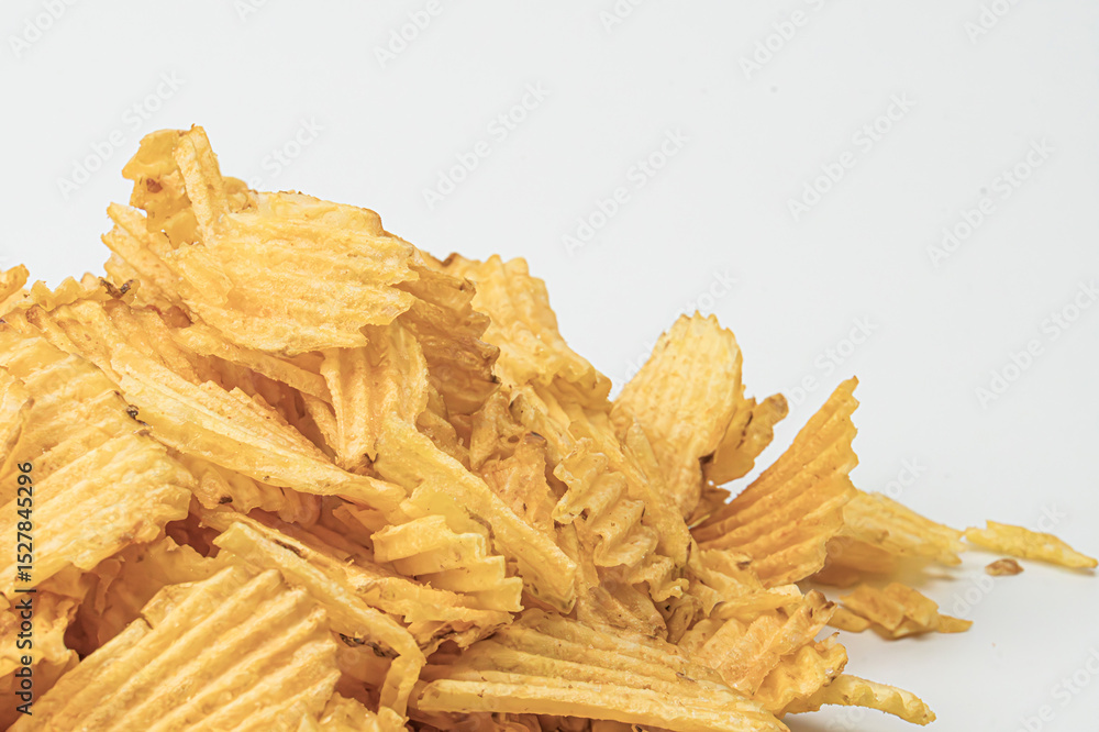 Poster close-up of yellow, ridged potato chips scattered on a gray surface with subtle shadows soft lightin