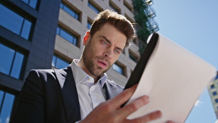 Fototapeta premium Frustrated manager analysing documents standing business street closeup. 