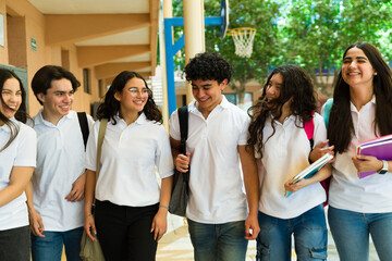 Happy high school students wearing white polo shirts walking and talking together