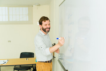 Smiling teacher writing on whiteboard in classroom