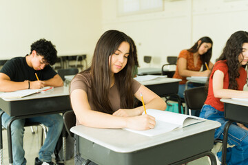 Focused high school students taking exam in classroom