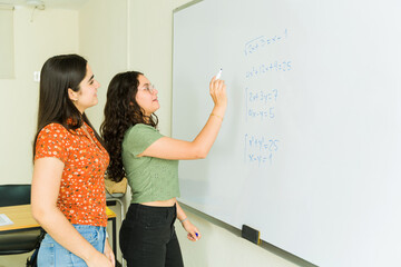 High school students solving math equations together on whiteboard