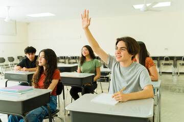 Hispanic high school student raising hand in classroom during lesson