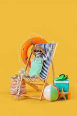 Human skeleton in deck chair with beach accessories on yellow background