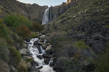 La Fragua waterfall low angle view with some goats eating grass around. Tourist destination in Neuquen, Patagonia, Argentina