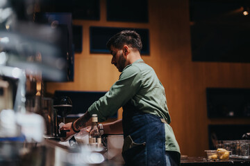 A professional coffee maker in a modern shop expertly crafts high-quality beverages. The atmospheric lighting highlights the skill and focus of the barista as he prepares coffee drinks.