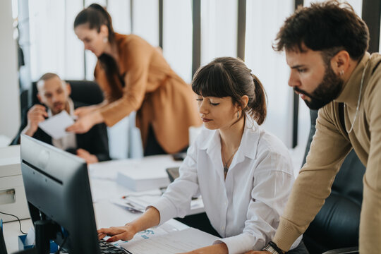 Group of coworkers collaborating in a modern office setting, showcasing teamwork and focus.