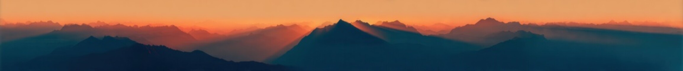 Obraz premium A panoramic view of mountains at sunrise, with the sun's rays piercing through them
