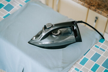 Iron resting on blue fabric on an ironing board in a laundry room