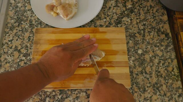 A piece of meat is being cut on a wooden cutting board