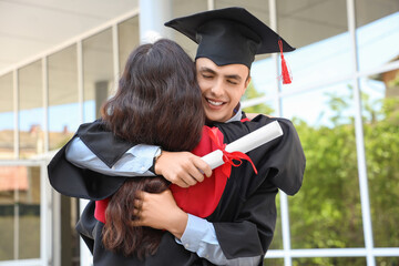 Couple of students with diploma hugging on their graduation day
