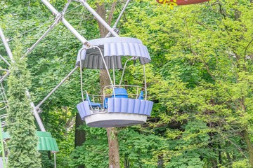 A vibrant amusement park image features a spinning gondola carousel with multiple blue cars, set...