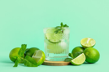 Glass of fresh Mojito cocktail with mint and limes on turquoise background