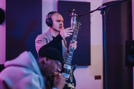 Two musicians working together in a recording studio. One is holding a guitar and singing into a microphone. The atmosphere is focused and creative, capturing the essence of musical collaboration.