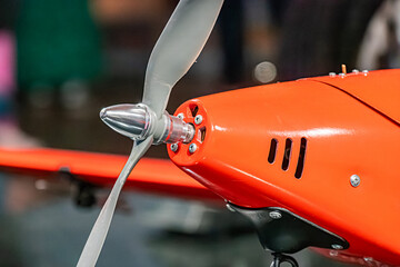 Close-up view of a stationary, indoor orange drone with reflective material, rotor blades at rest,...