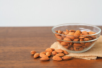 Almonds in glass bowl on wooden table background