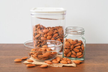Almonds in glass bowl on wooden table background. Almonds in glass jar.