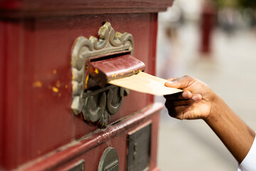 Close up view of hand inserting mail into mailbox. Post office service.