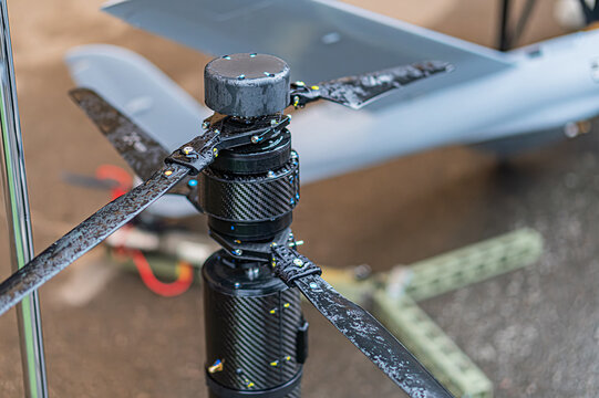 Image of a combat quadcopter drone, centrally positioned with a front-mounted gimbal The gimbal has multiple LED lights and a black protective shroud, suggesting it houses a camera or sensor assembl