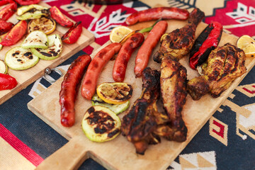 Grilling vegetables, sausages, and trout over charcoal in a backyard during summer. Outdoor cooking with real flames and smoke in a cozy home setting