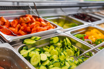A vibrant salad bar featuring trays of fresh cucumbers, tomatoes, and bell peppers with metal utensils, likely in a luxury resort in Cyprus.