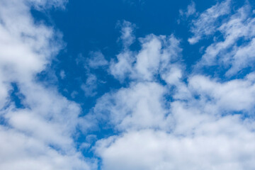 A serene view of fluffy white clouds scattered across a vibrant blue sky, creating a peaceful and tranquil atmosphere—perfect for nature, weather, or background themes.