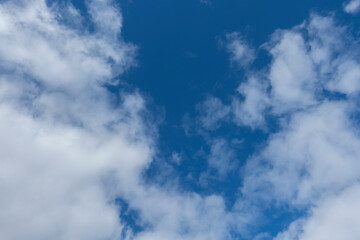 A serene view of fluffy white clouds scattered across a vibrant blue sky, creating a peaceful and tranquil atmosphere—perfect for nature, weather, or background themes.