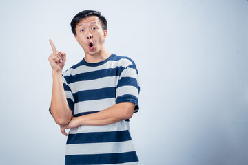 Asian man in navy and white striped t-shirt raising one index finger with an enthusiastic smile,...