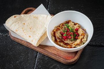 Savoring a hearty serving of hummus topped with pomegranate seeds, accompanied by fresh flatbread