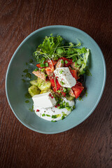 Colorful salad with mixed greens, cucumber, tomatoes, and creamy herb cheese, ready to enjoy