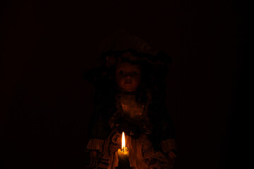 Vintage doll in classic royal dress with candle in the dark