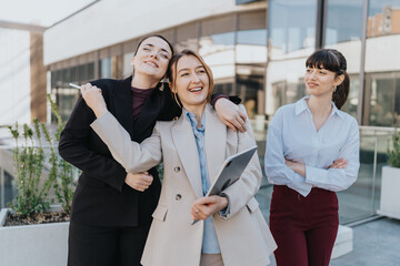 Three businesswomen enjoying a friendly moment outdoors. Their demeanor shows professionalism and...